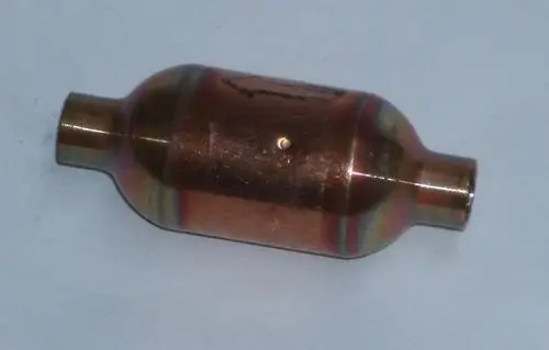Metallischer Schalldämpfer mit runder Form und zwei Anschlüssen. Produkt von Daikin, verwendet zur Geräuschreduzierung in Heizsystemen.